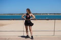 Blonde, young and beautiful woman dressed in black skirt and black top is on the promenade of the sea. The girl is doing different Royalty Free Stock Photo