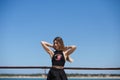 Blonde, young and beautiful woman dressed in black skirt and black top is on the promenade of the sea. The girl puts her hands Royalty Free Stock Photo