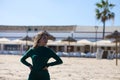 Blonde, young and beautiful woman dressed in an elegant green dress, standing on the seashore and doing different body poses. In Royalty Free Stock Photo