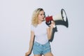 Blonde young cool girl with a megaphone isolated on white background Royalty Free Stock Photo