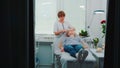 Blonde young woman getting facial massage with a jade roller in beauty spa salon