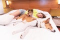 blonde young woman lying and sleeping in bed with her two collie dogs