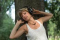 Blonde young woman in park listening to music on Royalty Free Stock Photo