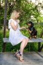 Blonde young woman teaches a dog to give a paw. Vertical view