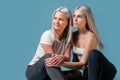 Blondehaired Mom and teenager daughter smiling on colorful backgroung. studio shoot with copy space