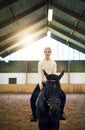 BlondeÃ¯Â¿Â½confident female sitting astride dark horse