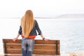 Blondie young woman back view, sea beach bench.