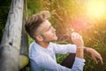 Blondish, blue eyed young man on wood fence