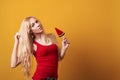 Blondy girl holding big candy looking at camera isolated over yellow background. Royalty Free Stock Photo