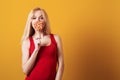 Blondy girl holding big candy looking at camera isolated over yellow background. Royalty Free Stock Photo