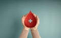 Blood Donation Concept. Help, Care, Love, Support. Hand Holding a Red Drop and Cross Sign Royalty Free Stock Photo
