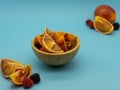 Blood orange cut in a wooden bowl in the center of the image with oranges around it, on a blue background. Healthy food concept Royalty Free Stock Photo