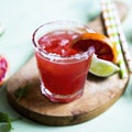 Blood orange and lime margarita cocktail with slices of fresh fruit and ice on optimistic green background Royalty Free Stock Photo