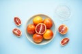 Blood oranges and glass juicer on blue background. Top view