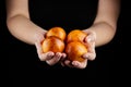 Blood oranges with red peel in hands on black background