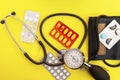 Blood pressure monitor and heart-shaped pills. Analogy with drugs for heart disease. Yellow retro background Royalty Free Stock Photo