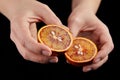 Blood or red orange fruit halves in hands on black background Royalty Free Stock Photo