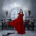 Bloodthirsty female vampire in red dress. Medieval interior Royalty Free Stock Photo