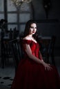 Bloodthirsty female vampire in red dress. Medieval interior Royalty Free Stock Photo