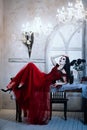 Bloodthirsty female vampire in red dress. Medieval interior Royalty Free Stock Photo