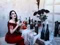 Bloodthirsty female vampire in red dress. Medieval interior Royalty Free Stock Photo