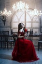 Bloodthirsty female vampire in red dress. Medieval interior Royalty Free Stock Photo