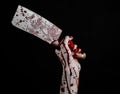 Bloody Halloween theme: bloody hand holding a large bloody kitchen knife on a black background isolated