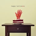 Bloody hand in a cake and text happy halloween