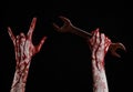 Bloody hand holding a big wrench, bloody wrench, big key, bloody theme, halloween theme, crazy mechanic, black background Royalty Free Stock Photo