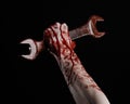 Bloody hand holding a big wrench, bloody wrench, big key, bloody theme, halloween theme, crazy mechanic, black background Royalty Free Stock Photo