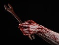 Bloody hand holding a big wrench, bloody wrench, big key, bloody theme, halloween theme, crazy mechanic, black background Royalty Free Stock Photo