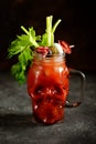 Bloody Mary cocktail in glass skull with celery sticks, pink salt, lime and canapes from canned vegetables. Halloween drink. Royalty Free Stock Photo