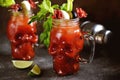 Bloody Mary cocktail in glass skull with celery sticks, pink salt, lime and canapes from canned vegetables. Halloween drink. Royalty Free Stock Photo