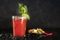 Bloody Mary cocktail with tomato juice, lime, and celery, wiuth pickles and a chili pepper, side view on a black background Royalty Free Stock Photo