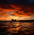 Bloody sunset in storm clouds over black sea waves