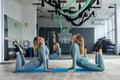 Bloody two young female trainers train in the hall performing exercises for health.