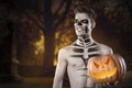 Bloody zombie man with brains out holding halloween pumpkin. Horror. Halloween.