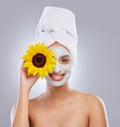 Bloom from within. an attractive young woman wearing a face mask and holding a sunflower over her eye in the studio. Royalty Free Stock Photo