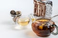 Blooming black tea in a glass teapot. On a light surface. Nearby are tea briquettes of leaves and flowers. In the background is a Royalty Free Stock Photo