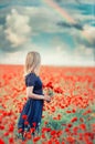 A blooming field of red poppies flowers and a girl with a bouquet of red poppies. Royalty Free Stock Photo