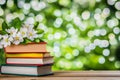 Blooming flowers in a serene outdoor spring setting enclose a stack of vintage books Royalty Free Stock Photo
