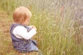 Blooming red poppies in a green summer field, a small child in jeans sits on the grass, touches the spikelets, the concept of