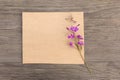 Blooming sally purple flowers with craft paper blank on old grunge wooden background. Top view. Minimalistic mockup. Royalty Free Stock Photo