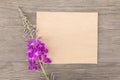 Blooming sally purple flowers with craft paper blank on old grunge wooden background. Top view. Minimalistic mockup. Royalty Free Stock Photo