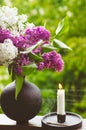 Blooming spring lilac flowers and burning candle in a candlestick. Spring background Royalty Free Stock Photo