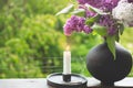 Blooming spring lilac flowers and burning candle in a candlestick. Spring background Royalty Free Stock Photo