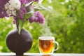 Blooming spring lilac flowers and hot cup tea. Spring background Royalty Free Stock Photo