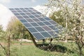 Blooming trees on the background of a home solar panel on the bed. Production of electroenergy for the home, solar panels near the Royalty Free Stock Photo