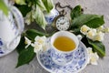 Blossoming tender jasmine flowers and a tea set with a mechanical clock on a chain. Royalty Free Stock Photo