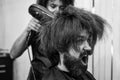 blow dry hair in barbershop of brutal mature shouting client man, hairdresser